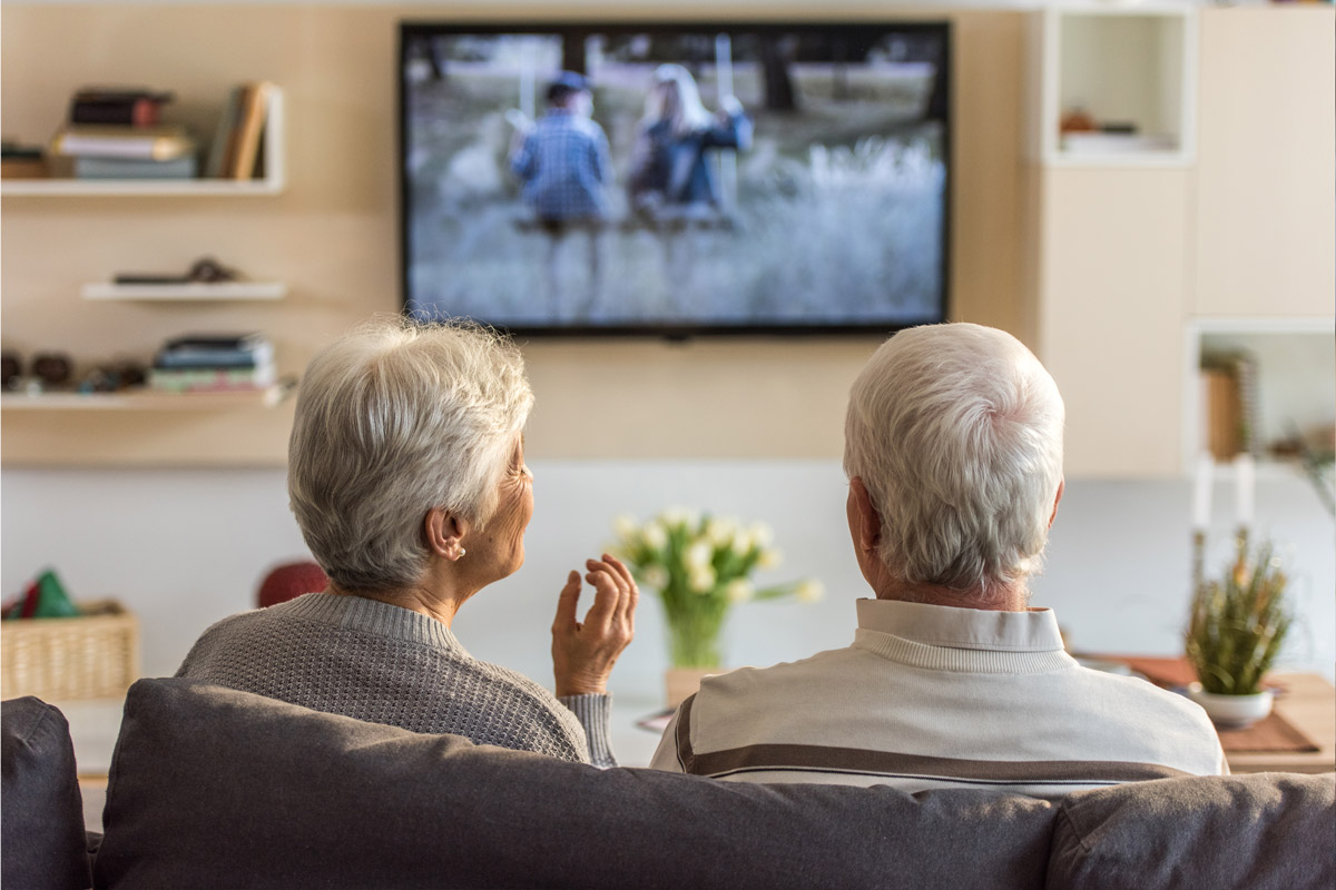 A senior couple watching television together with the Beltone Direct TV Link