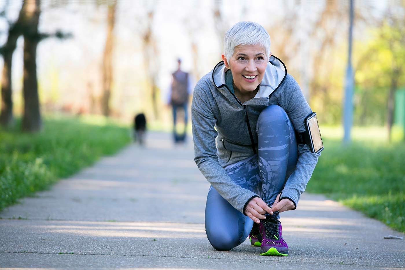 A senior woman wearing Beltone Ally Hearing Aids on a run and tying her shoes