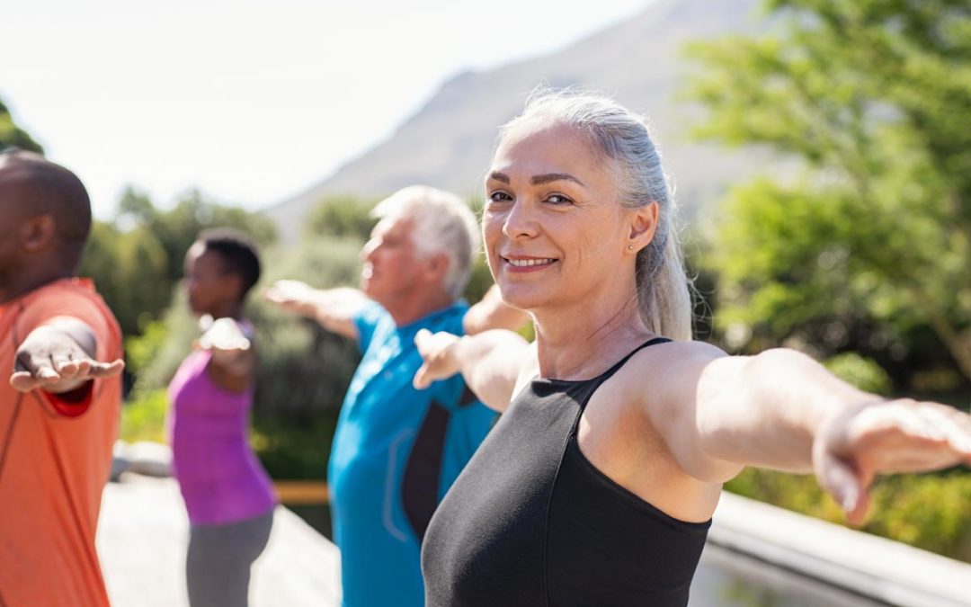 A healthy, senior woman wearing Beltone Hearing Aids does yoga with others