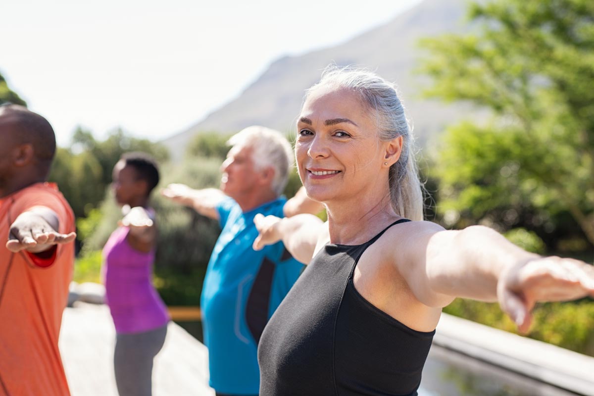 A healthy, senior woman wearing Beltone Hearing Aids does yoga with others