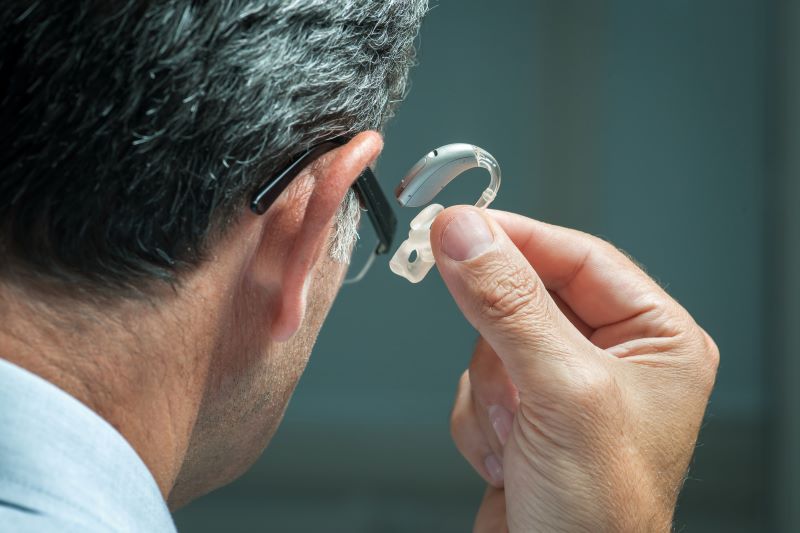 man holding hearing aid to his ear