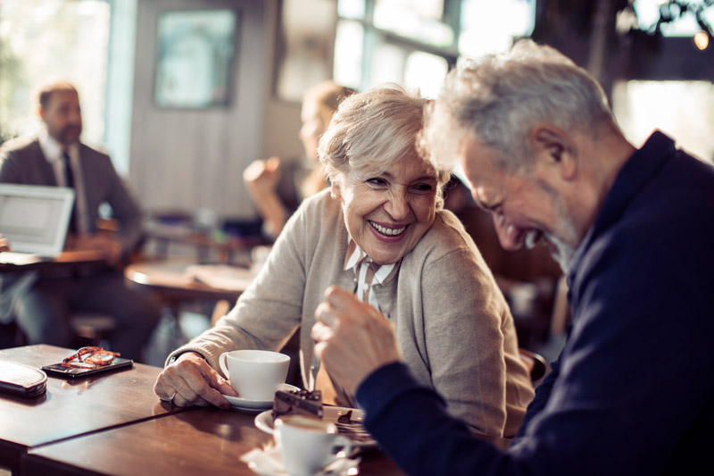 A senior couple laughing at a coffee shop