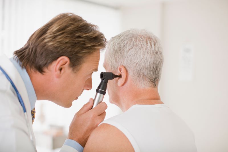 doctor looking in patient's ear with otoscope