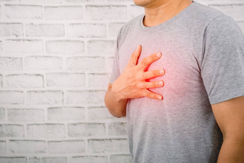 man experiencing heart disease symptoms holds his hand to his chest
