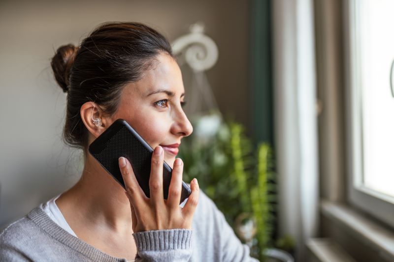 woman with hearing aid talks to insurance provider on smart phone