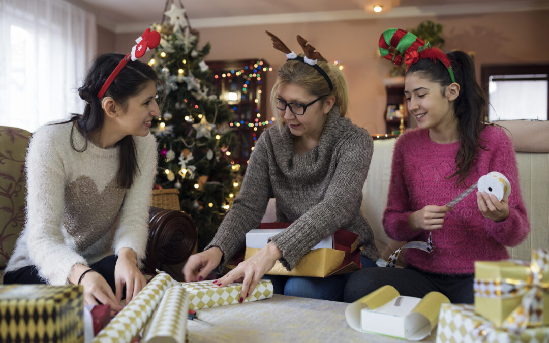 Mother with her daughters packaging Christmas gifts