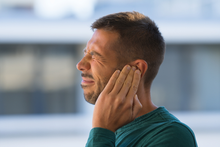 Man touching ear because of ear pain or tinnitus