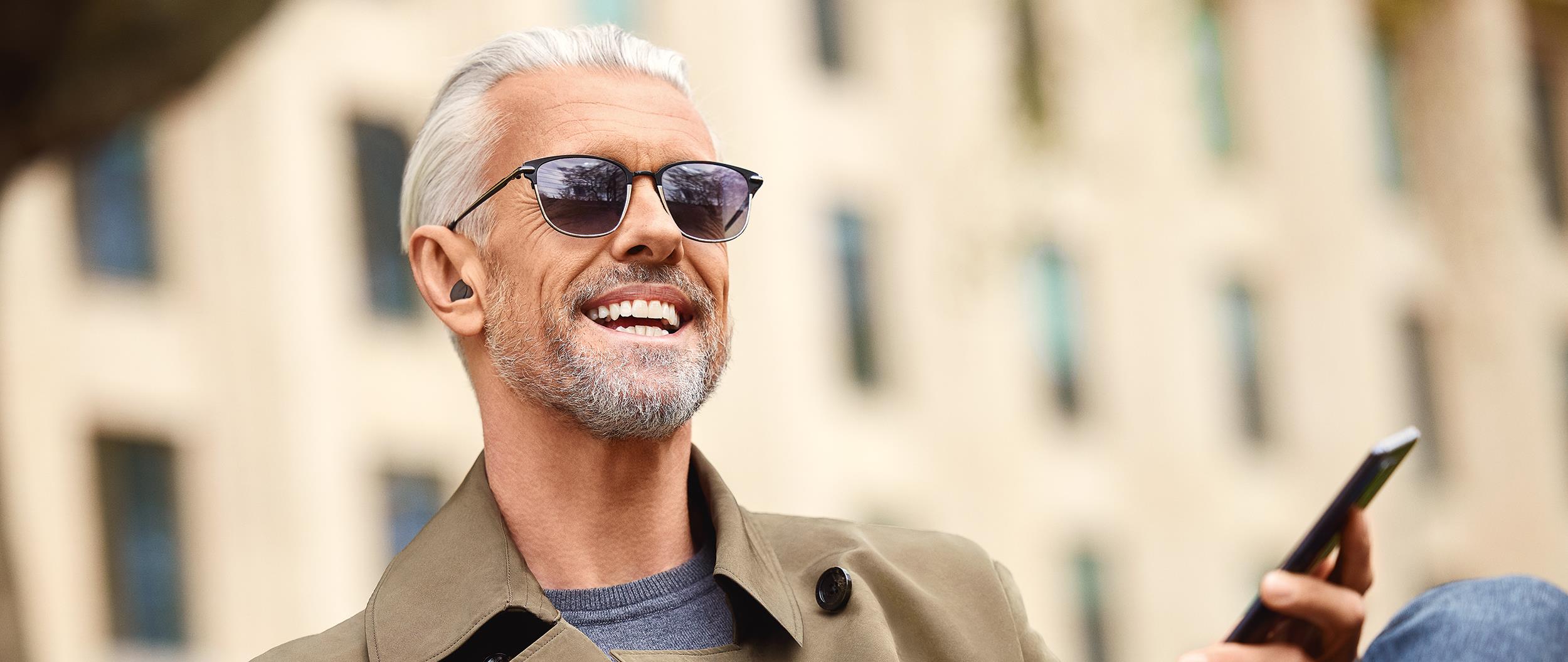 a man smiling while wearing Jabra Enhance™ Plus over-the-counter earbud hearing aids