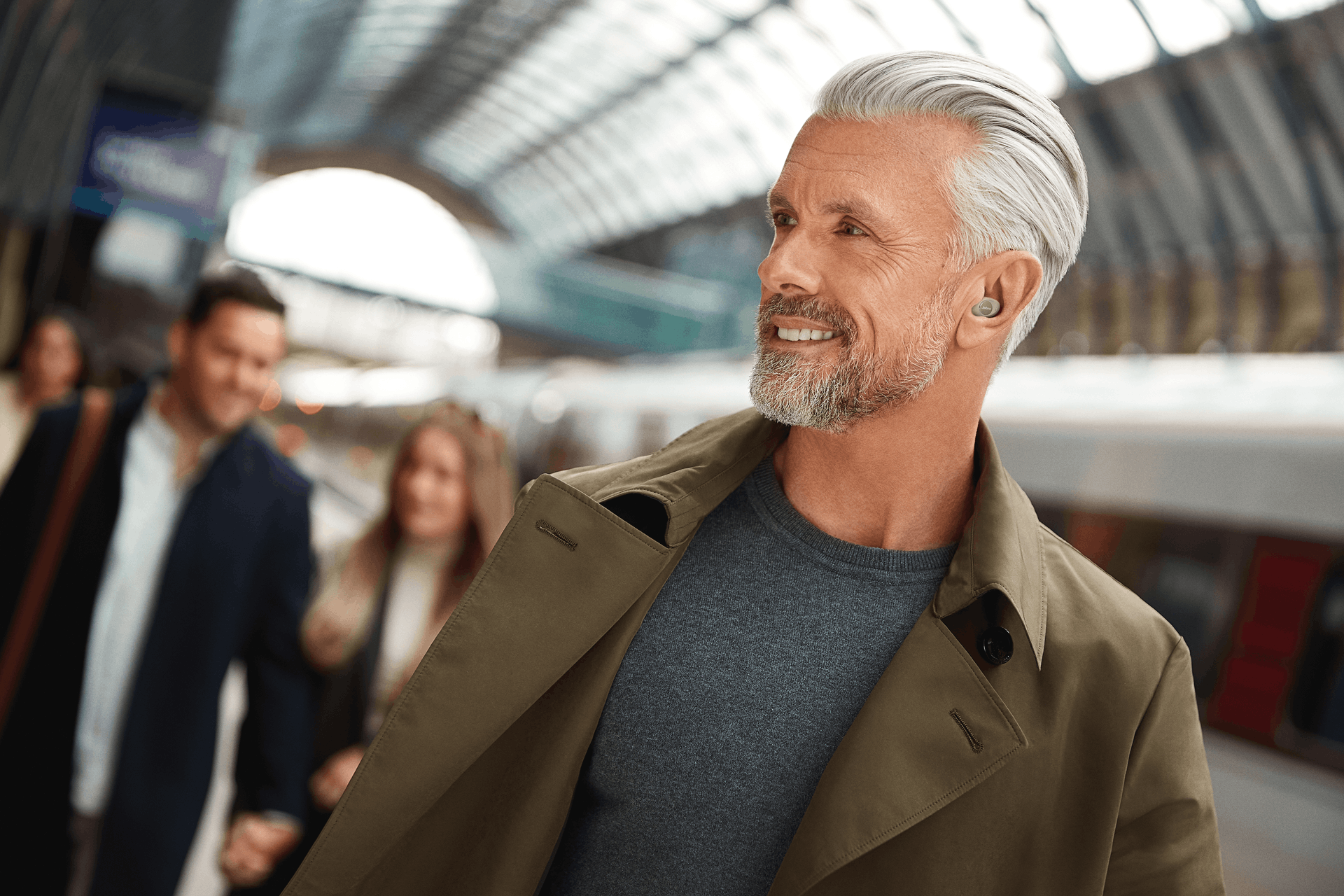 a man wearing Jabra Enhance™ Plus earbud hearing aids walking through a transit center
